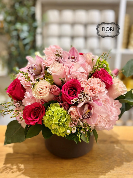 Luxury Mother's Day flower arrangement "Dolce Mamma" featuring hot pink roses, Cymbidium orchids, and green hydrangea in a chocolate ceramic vase. Oakville online Delivery