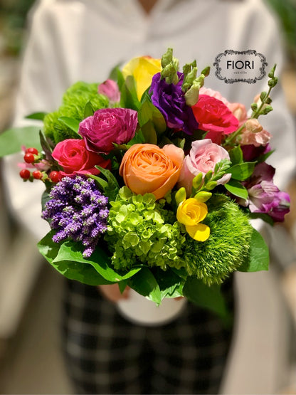 A mix of purple, yellow, pink, red, and greens in a white vase by FIORI Oakville, Oakville Flower Shop